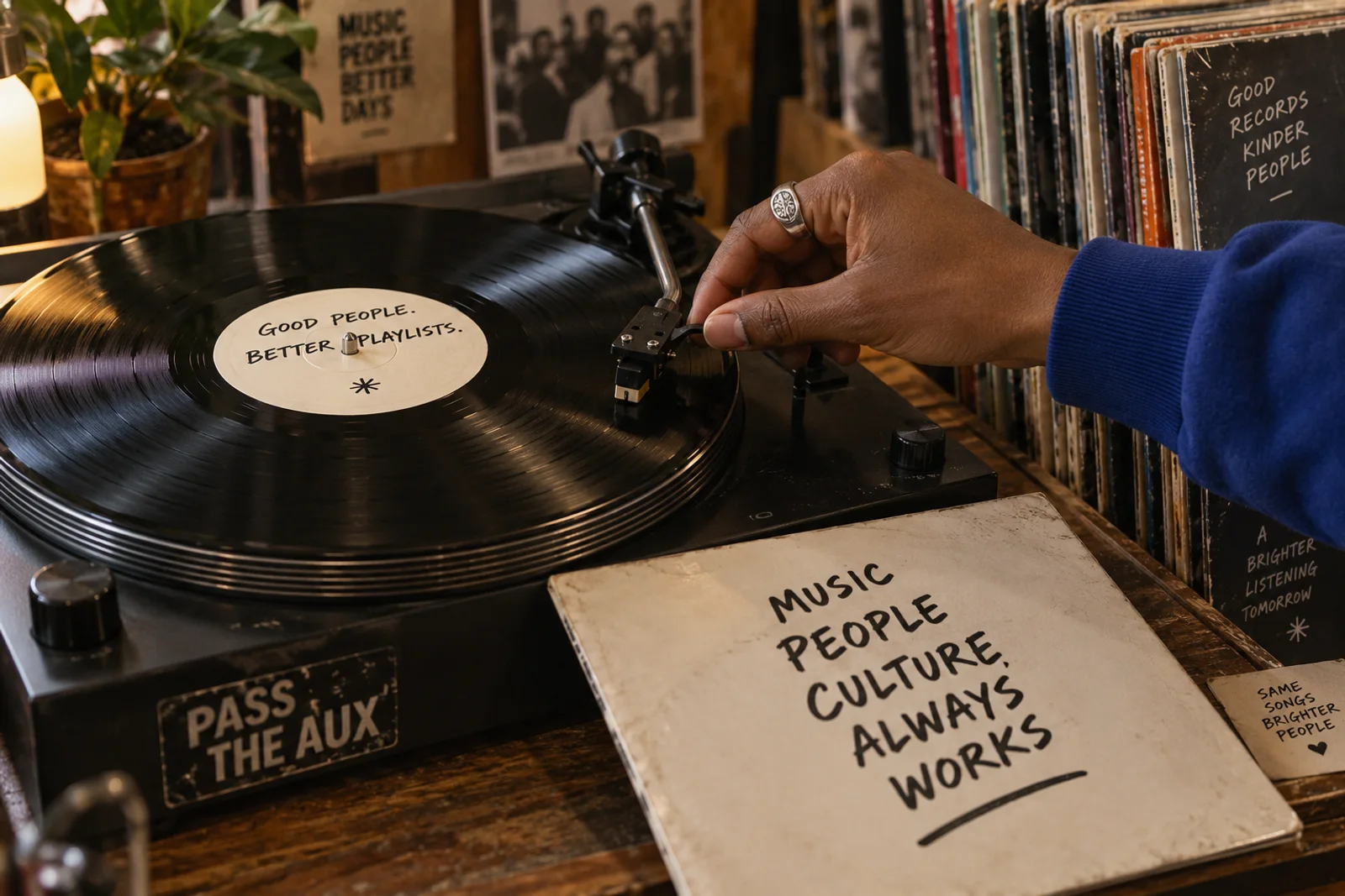 Concept imagery: a hand cues a vinyl record in a warm record store.
